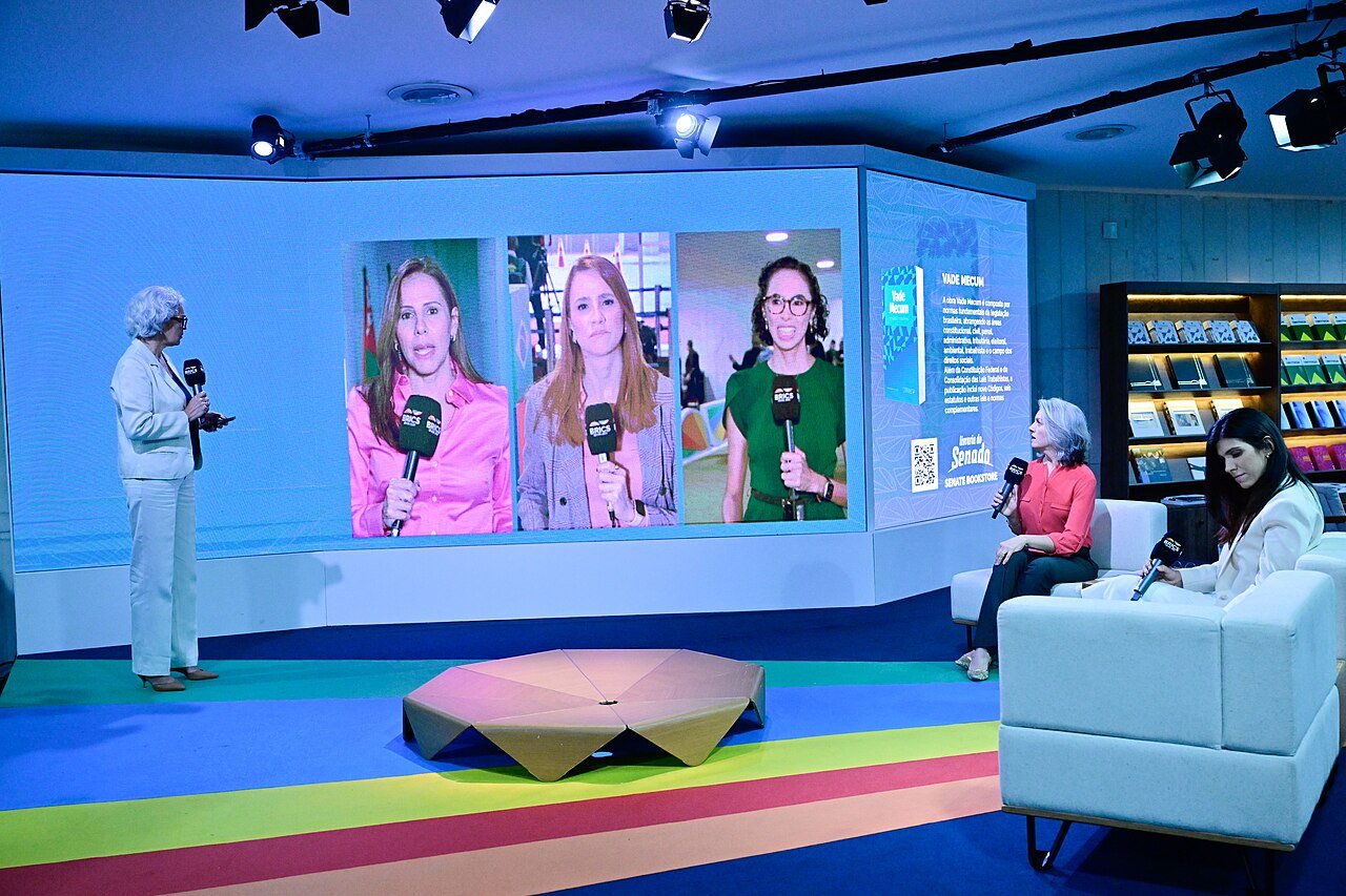 Estúdio de cobertura jornalística do Senado com repórteres exibidos em telão e entrevista ao vivo
