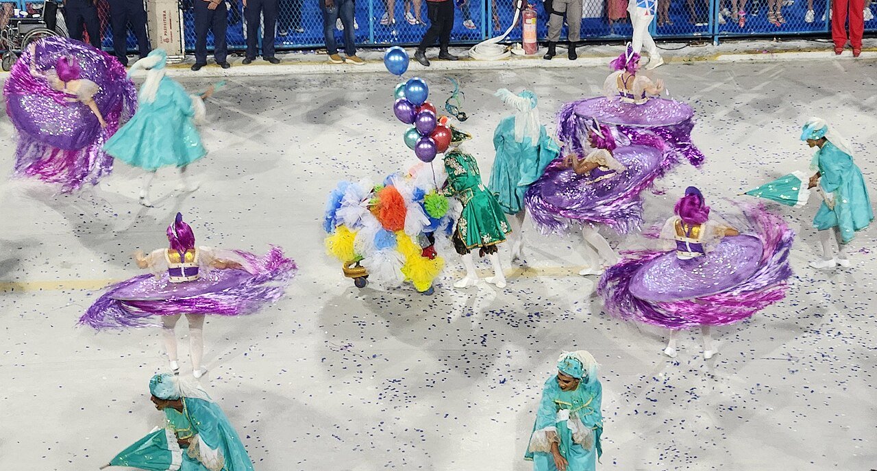 Componentes de escola de samba desfilam com fantasias coloridas na avenida