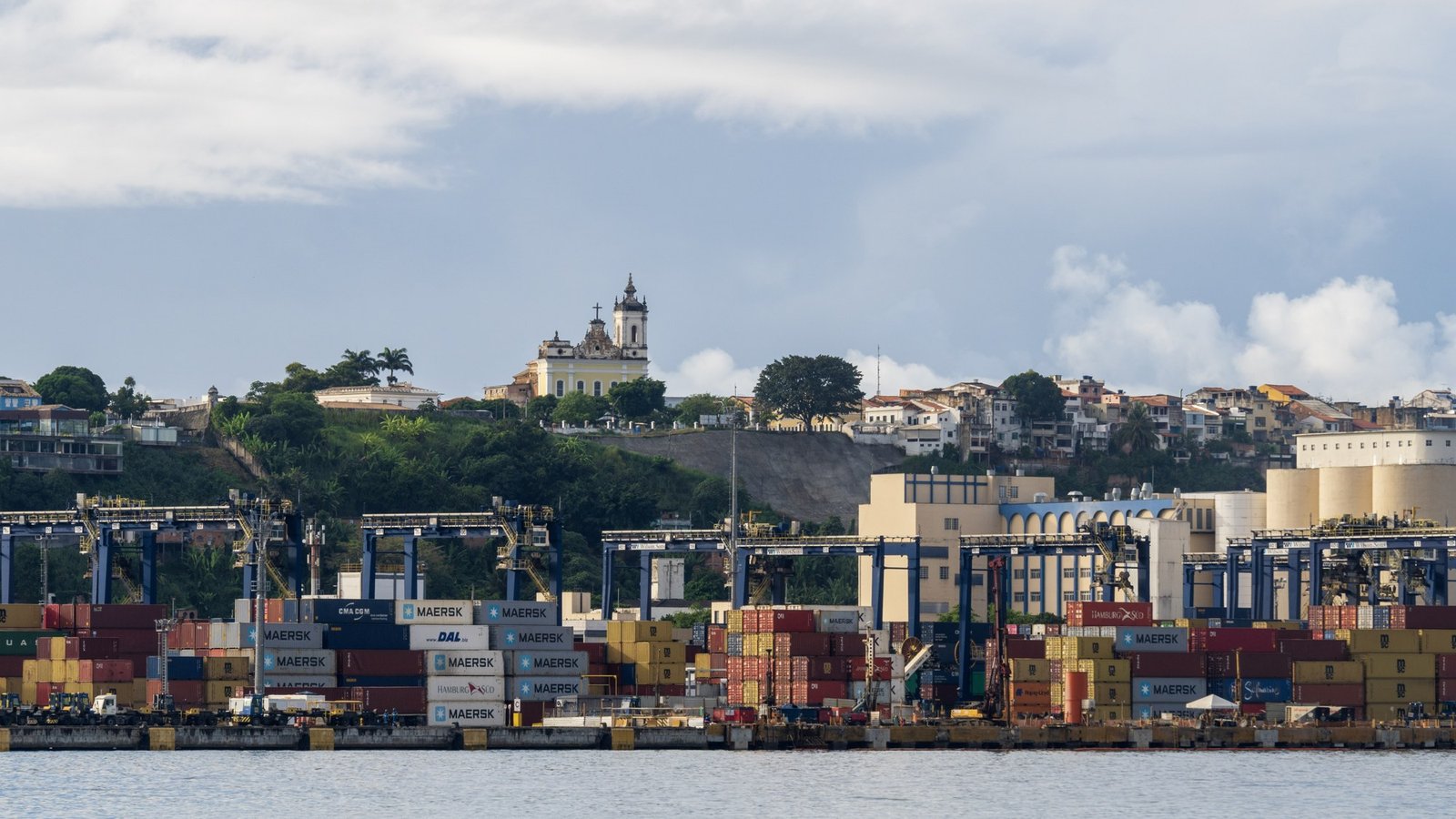 Guindastes e contêineres no Terminal de Cargas do Porto de Salvador, com o bairro do Santo Antônio ao fundo
