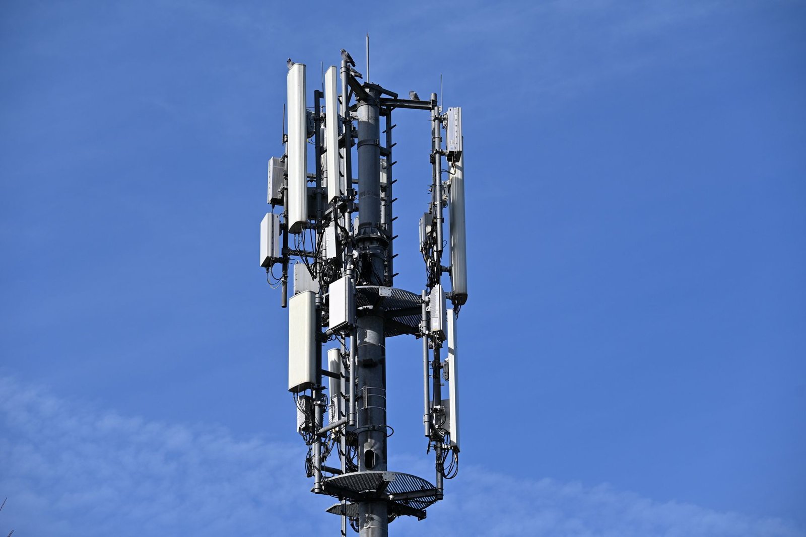 Torre de telefonia móvel com antenas setoriais e equipamentos de transmissão contra o céu azul