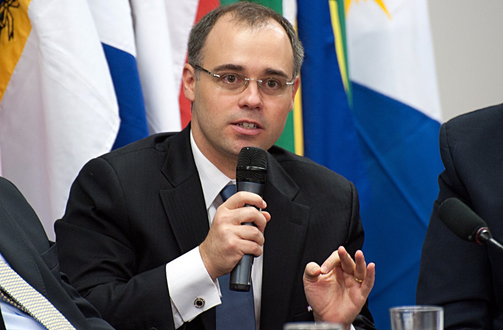 O ministro André Mendonça fala ao microfone diante de bandeiras, em imagem de arquivo de 2011