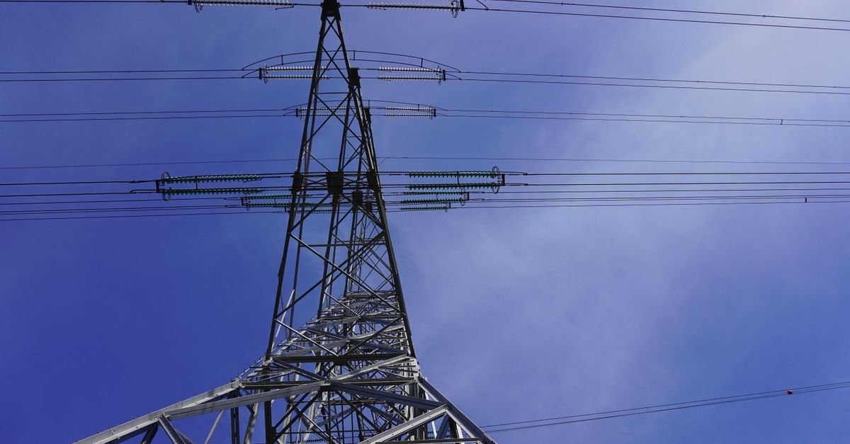 Torre de transmissão de energia elétrica vista de baixo contra o céu azul