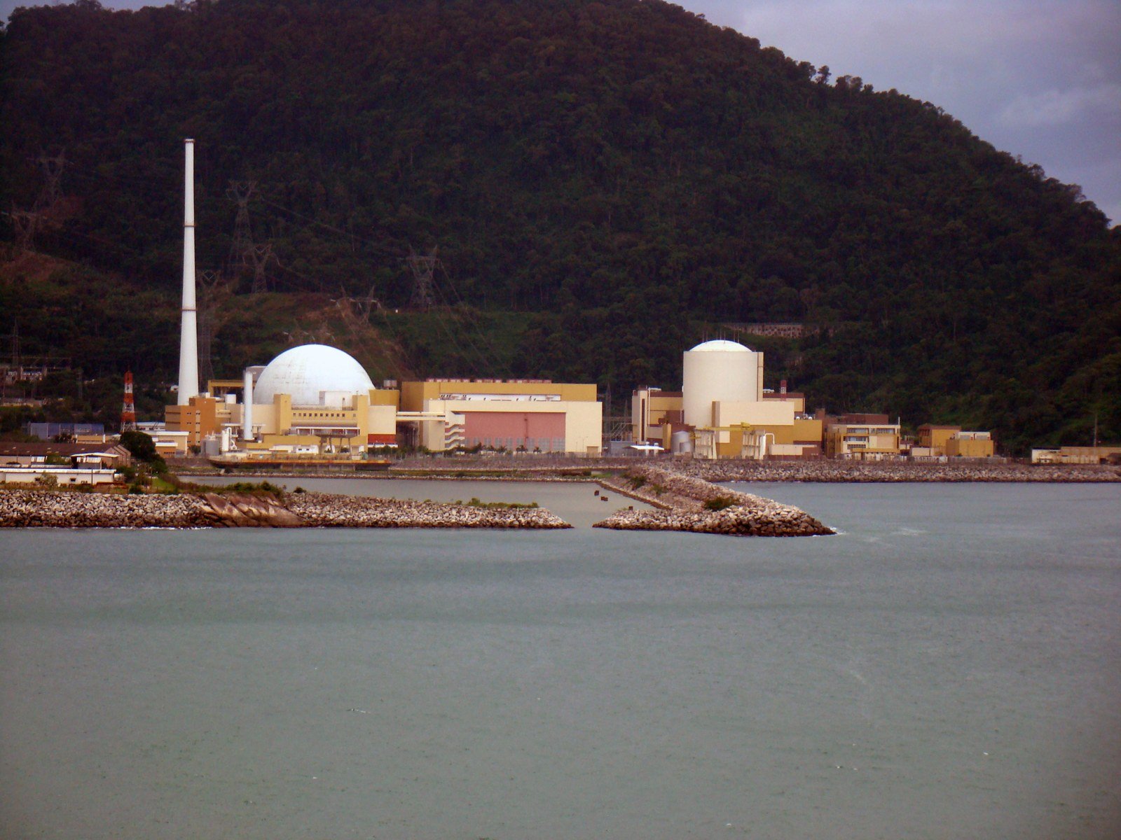 Complexo das usinas nucleares de Angra dos Reis (RJ) à beira-mar, com cúpula branca e chaminé; foto de arquivo das usinas em operação