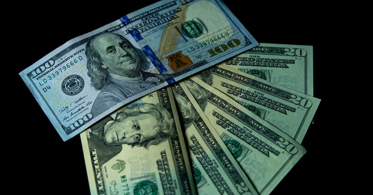 Cédulas de dólar americano de cem e vinte dólares sobre fundo escuro