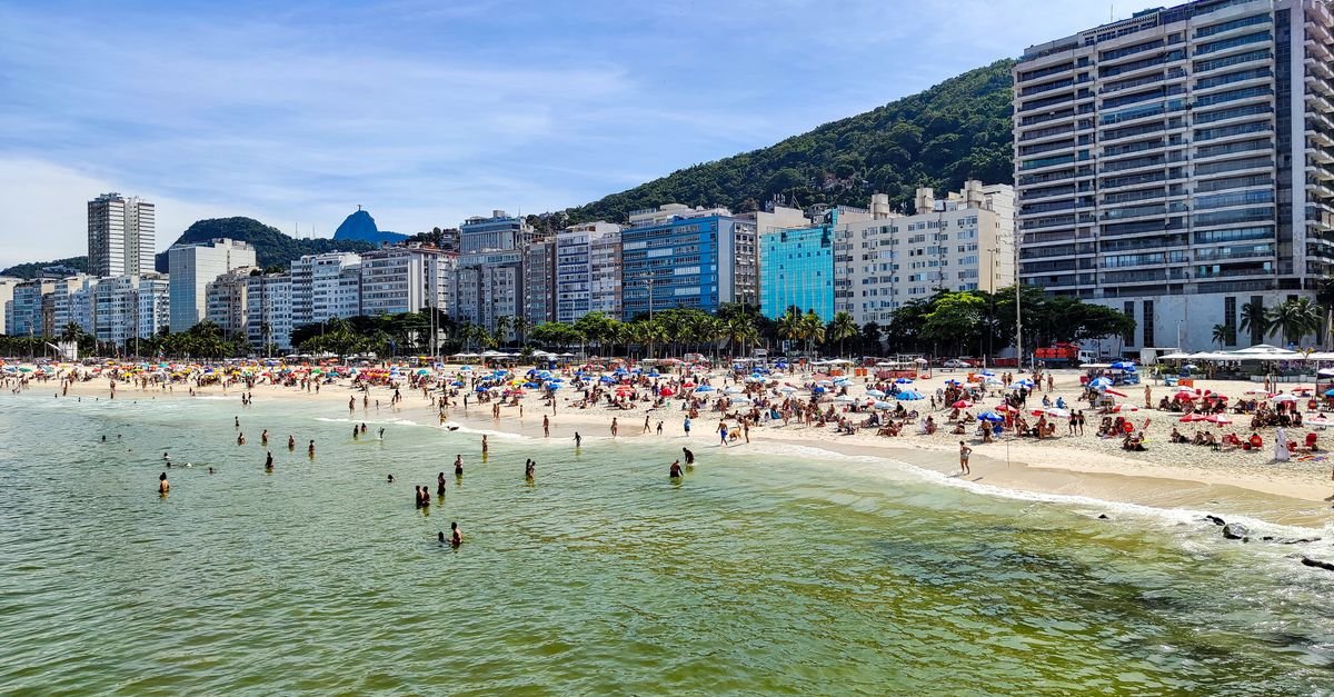Orla da praia de Copacabana, no Rio de Janeiro, com muitas pessoas na areia e na água