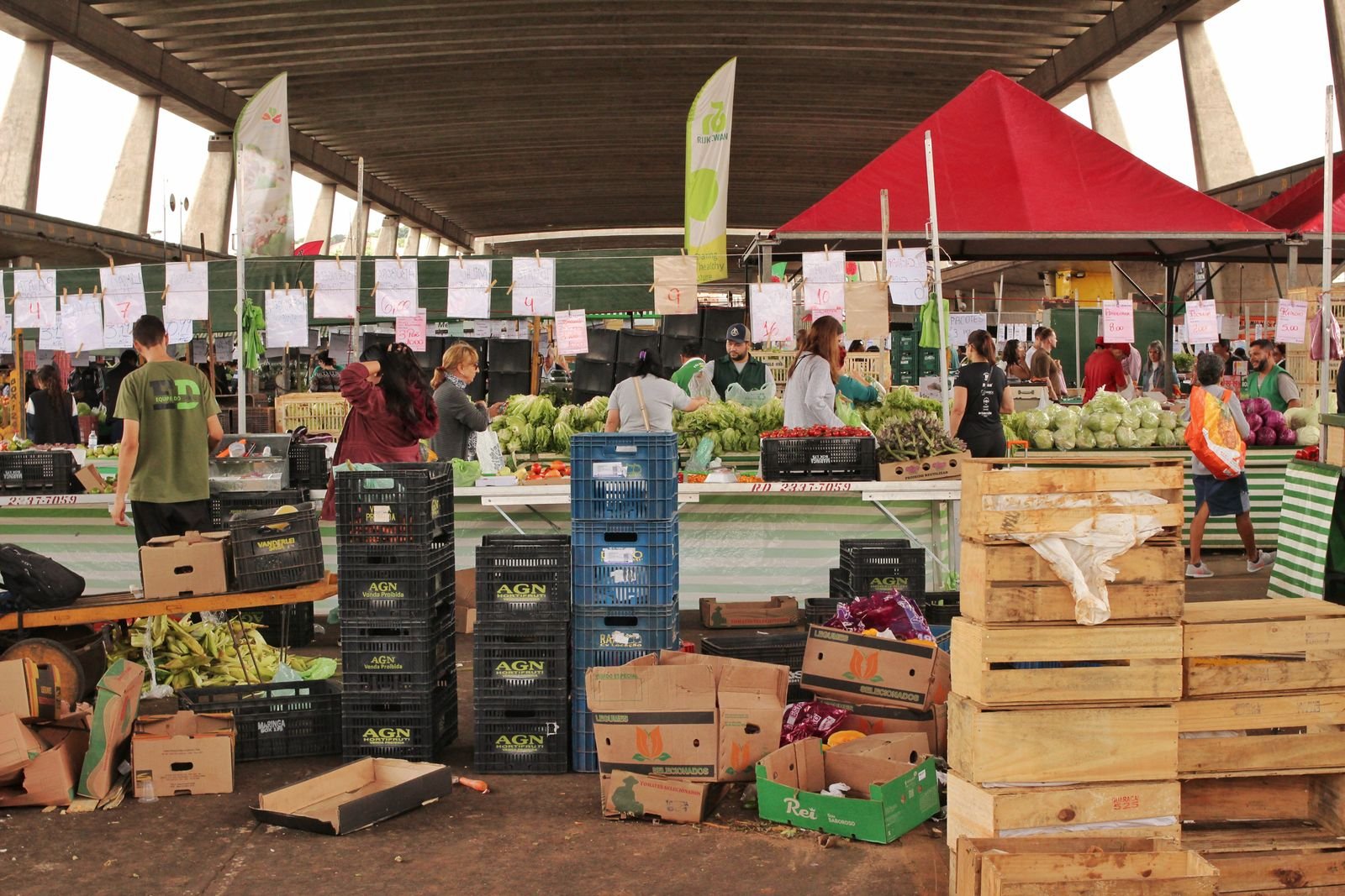 Bancas de hortifrúti em feira coberta de São Paulo, com clientes e vendedores
