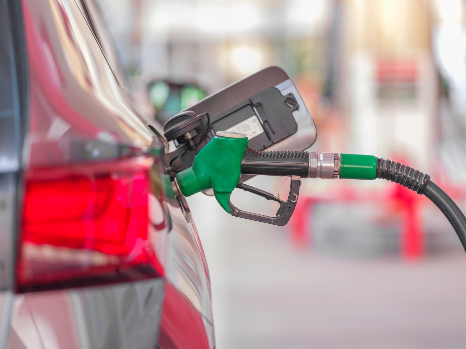 Bico de abastecimento verde encaixado no tanque de um carro em posto de combustível