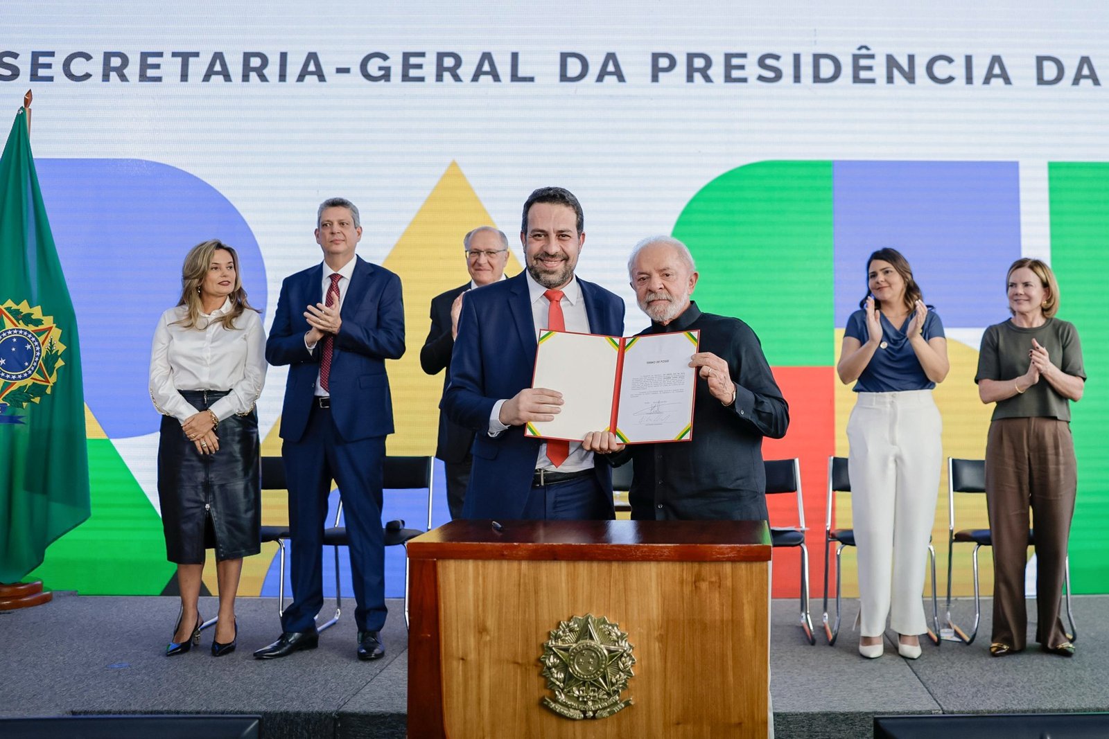 Guilherme Boulos segura o termo de posse ao lado do presidente Lula, em cerimônia no Palácio do Planalto