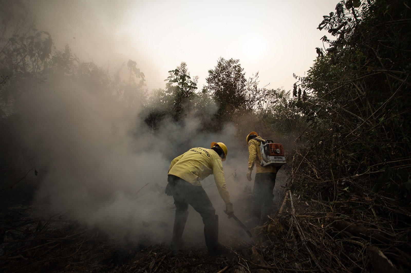 Dois brigadistas do Prev Fogo do Ibama combatem foco de incêndio em meio à fumaça no Amazonas
