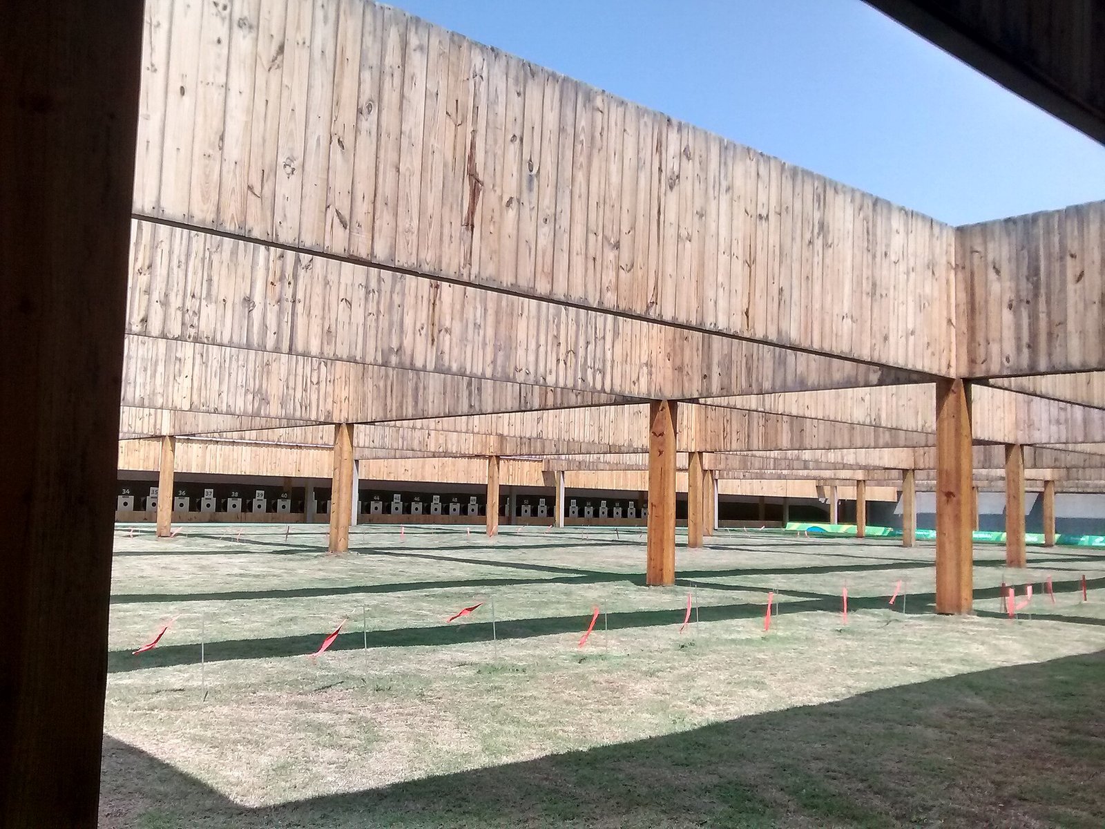Interior de um stand de tiro vazio, com alvos numerados alinhados ao fundo