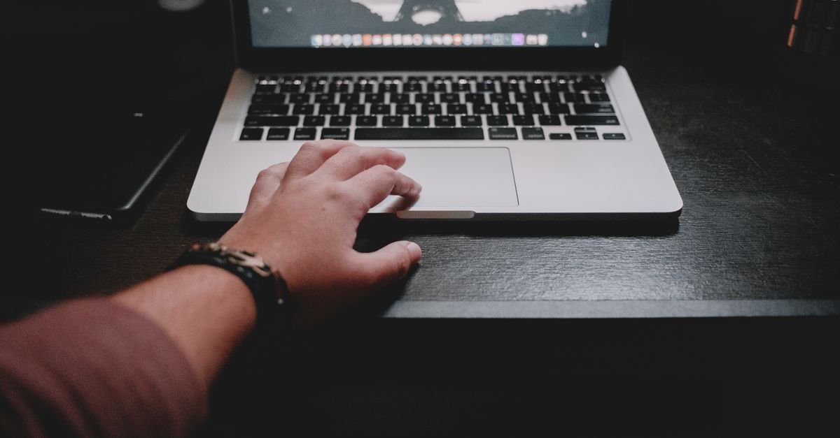 Mãos sobre o teclado de um notebook em ambiente escuro