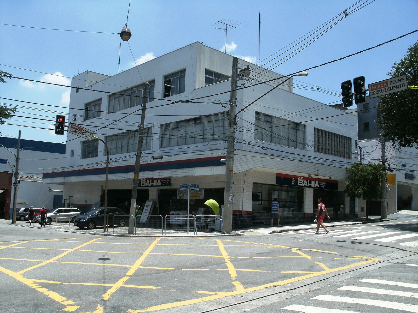 Fachada de uma loja das Casas Bahia em esquina de rua movimentada, com placas de trânsito em português