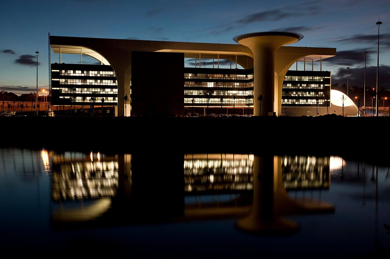 Cidade Administrativa de Minas Gerais ao anoitecer, com os predios refletidos no espelho d'agua