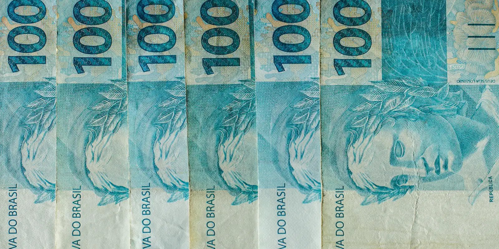 Cédulas de cem reais brasileiras enfileiradas lado a lado