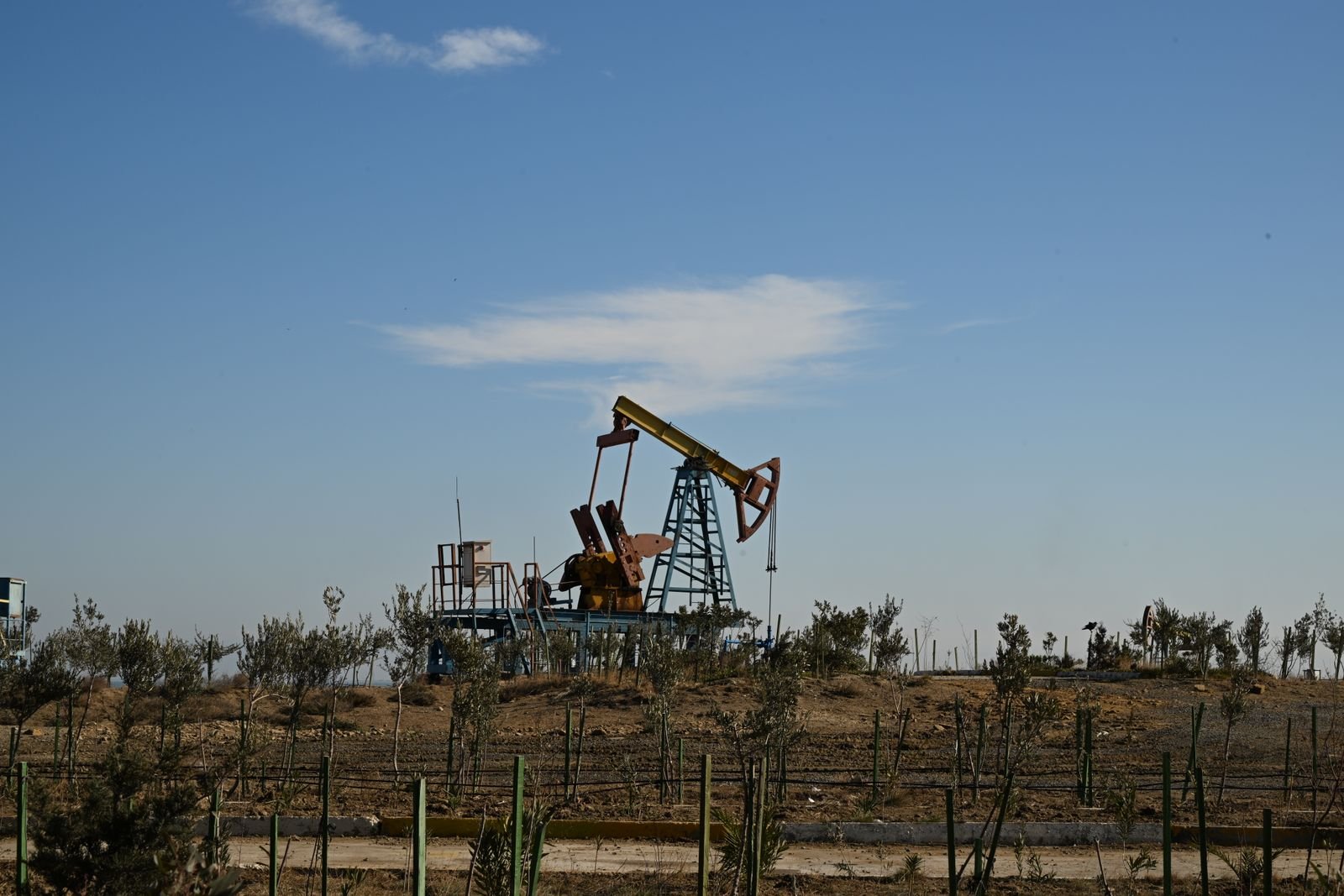Cavalo de pau de extração de petróleo em terreno seco, sob céu azul