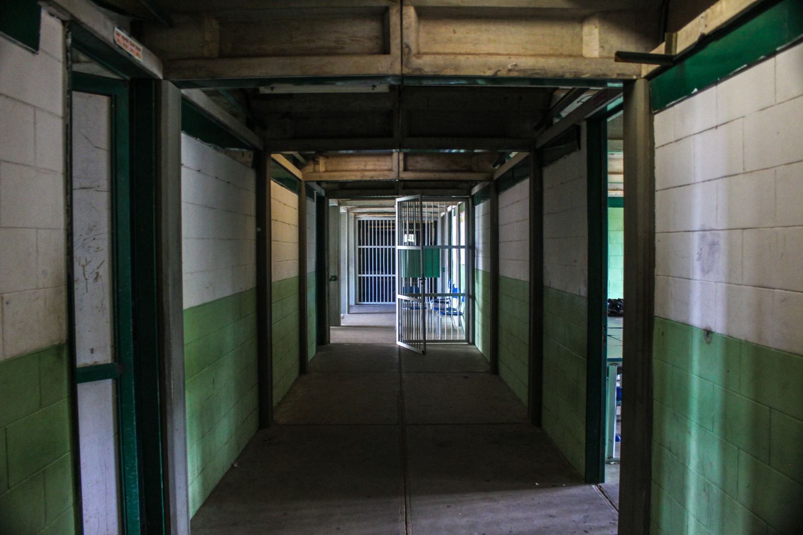 Corredor de presídio com portão gradeado aberto ao fundo, em foto de arquivo