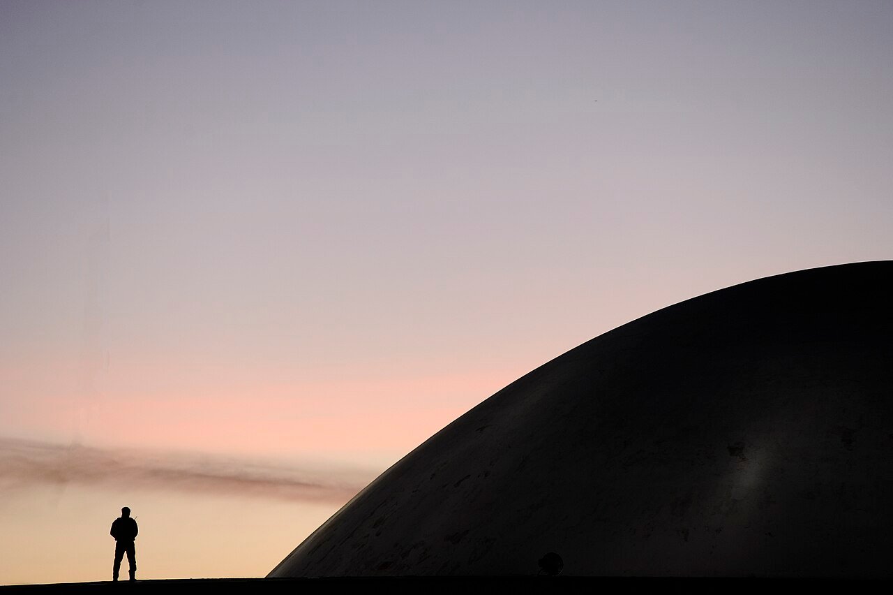 Cúpula do Senado Federal ao entardecer, em Brasília, com a silhueta de um segurança em primeiro plano (foto de arquivo)