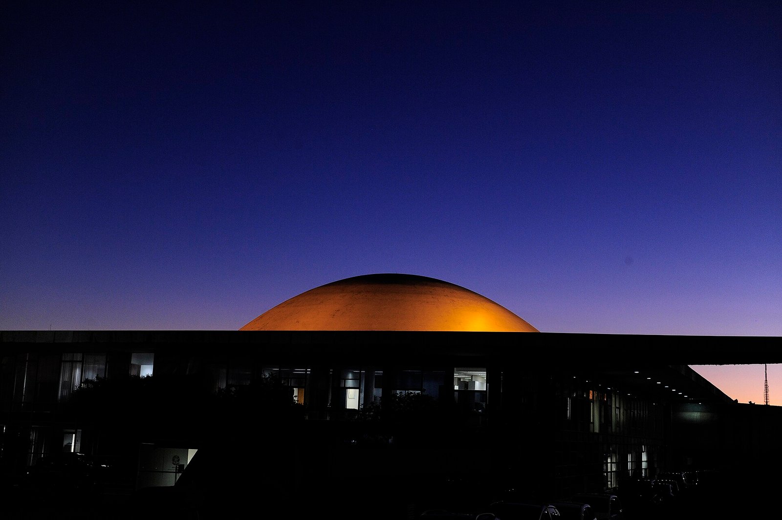 Cúpula branca do plenário do Senado Federal iluminada ao anoitecer, com o céu azul escuro ao fundo