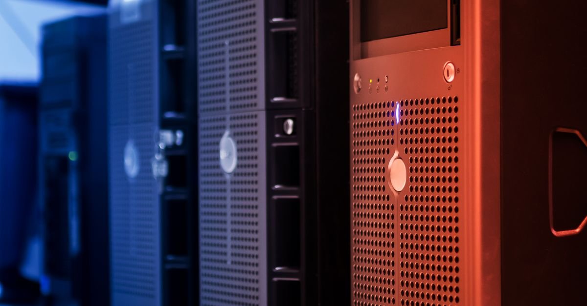 Racks de servidores enfileirados em data center, iluminados por luz azul e vermelha