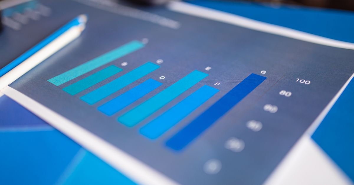 Gráfico de barras impresso em tons de azul sobre mesa de trabalho