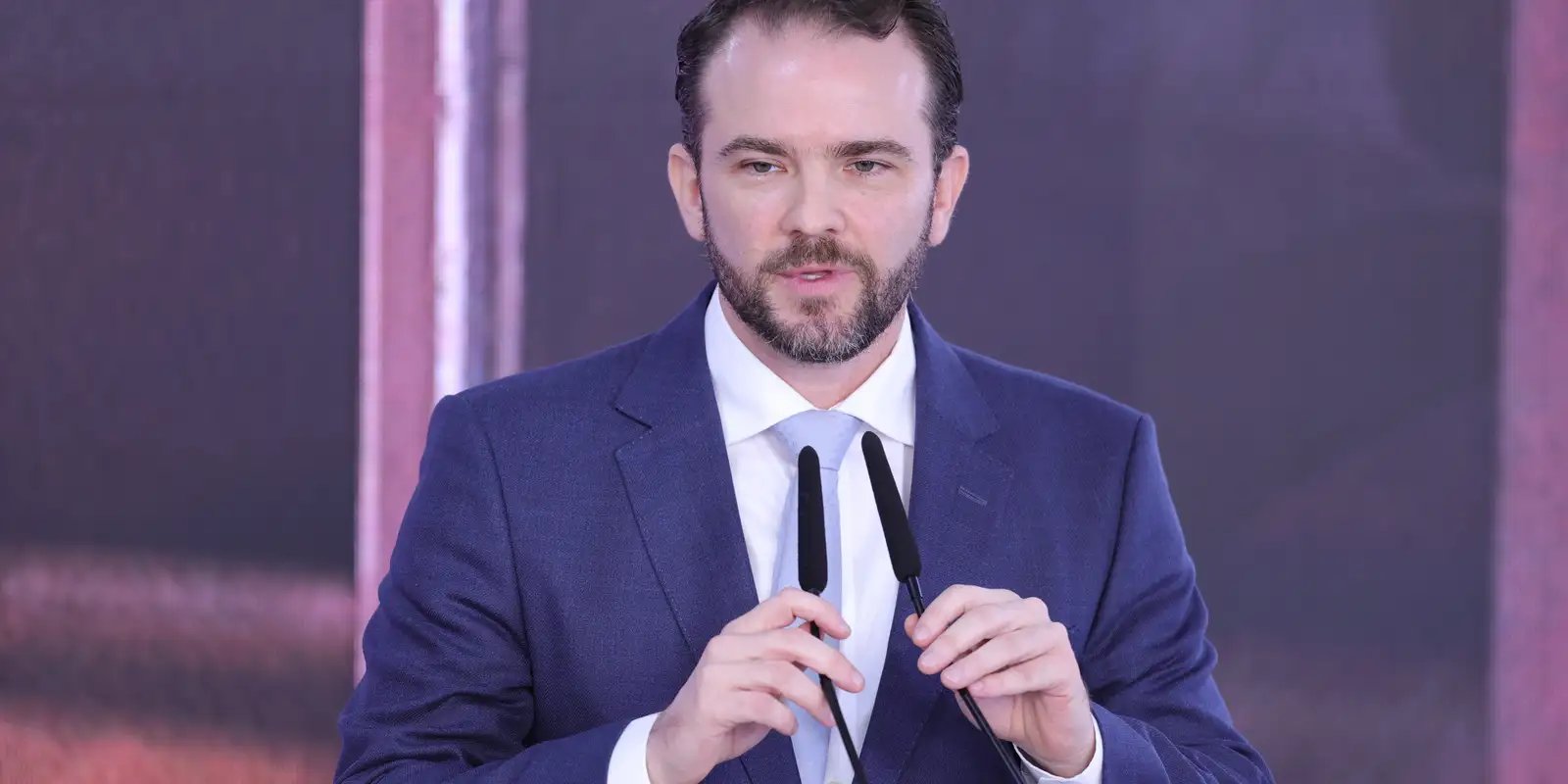 O ministro da Fazenda, Dario Durigan, fala com dois microfones à frente durante evento
