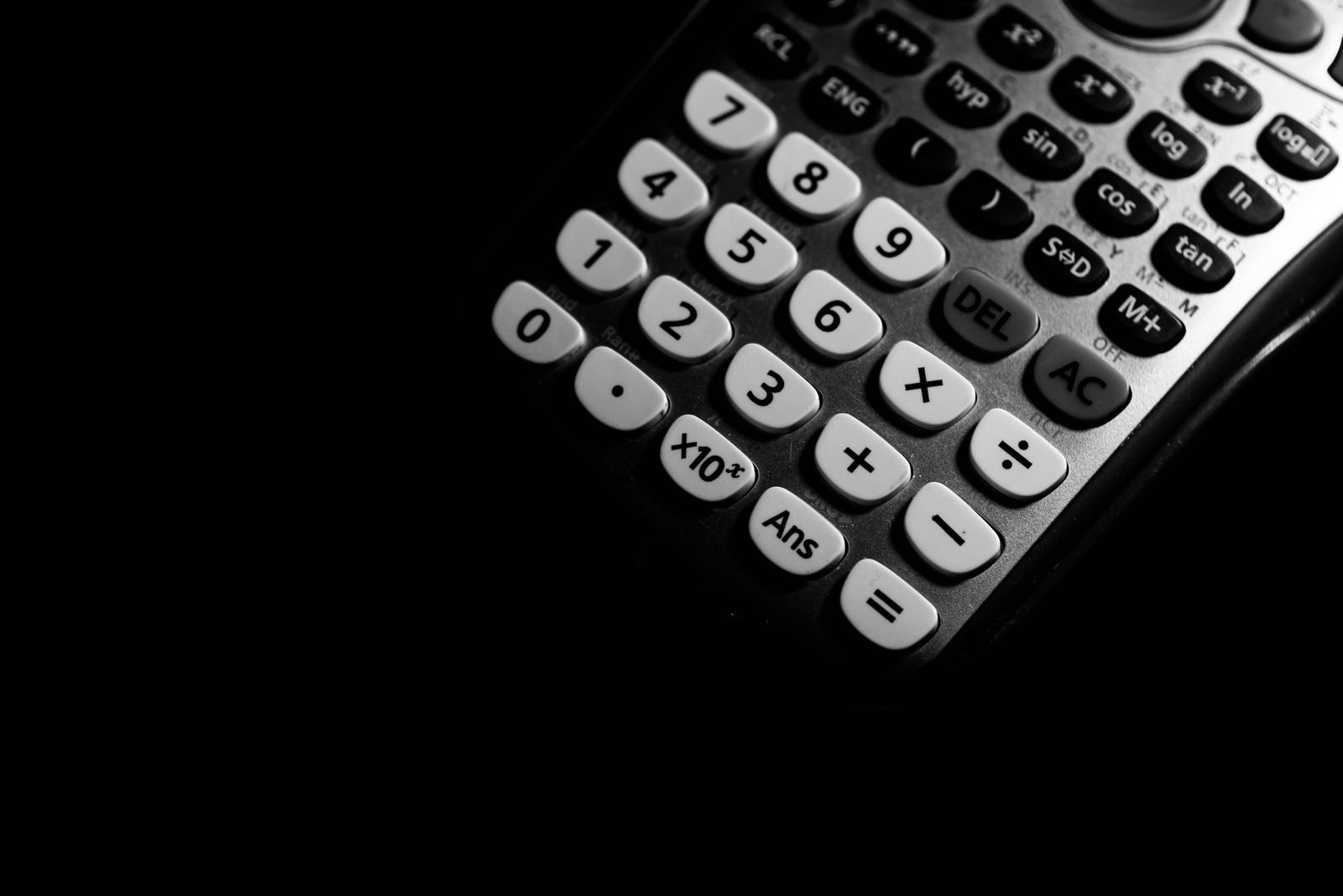 Teclado de uma calculadora científica em close, com teclas numéricas em destaque, sobre fundo escuro