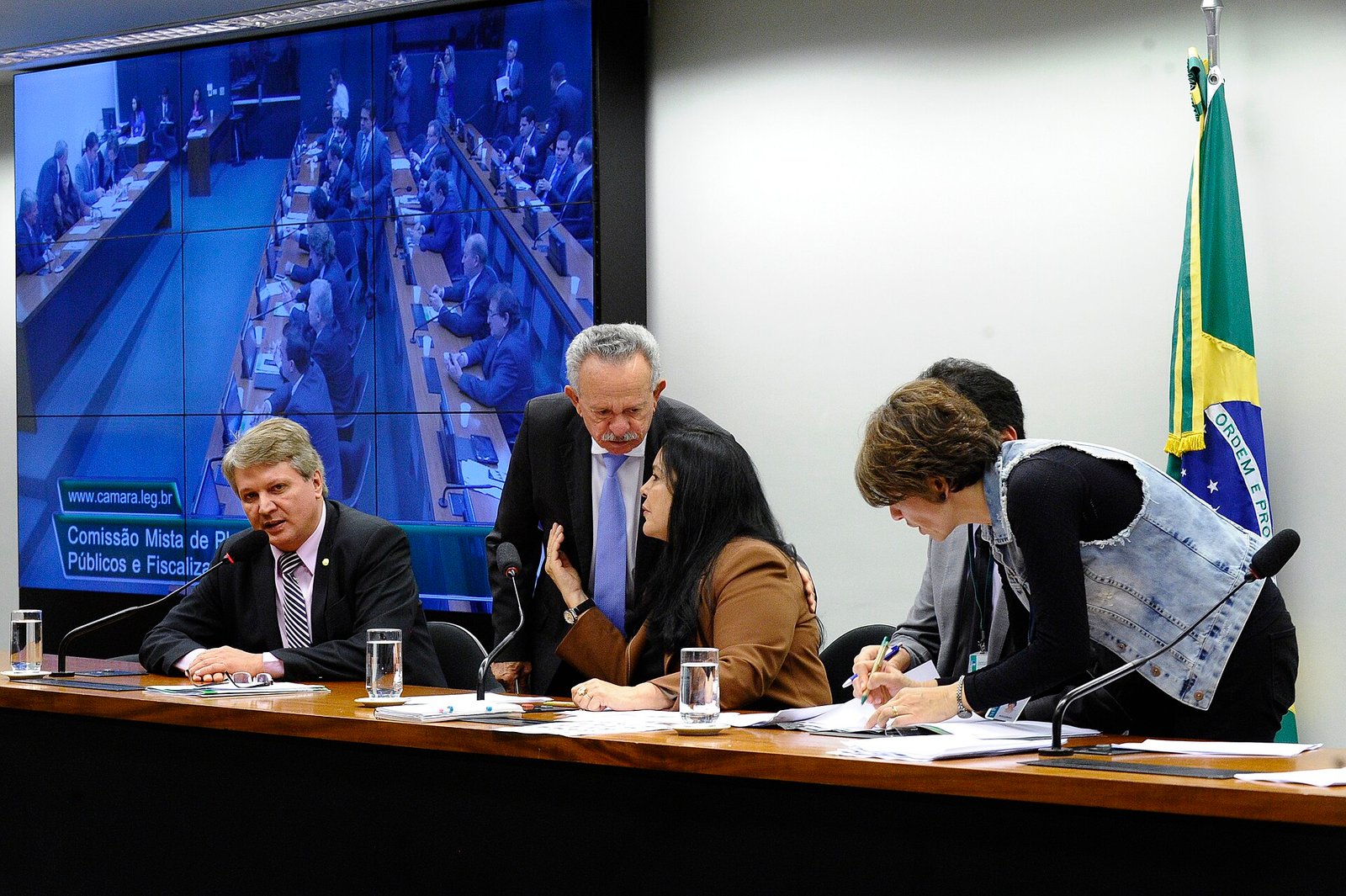 Mesa da Comissão Mista de Planos, Orçamentos Públicos e Fiscalização durante reunião, com painel do Congresso ao fundo