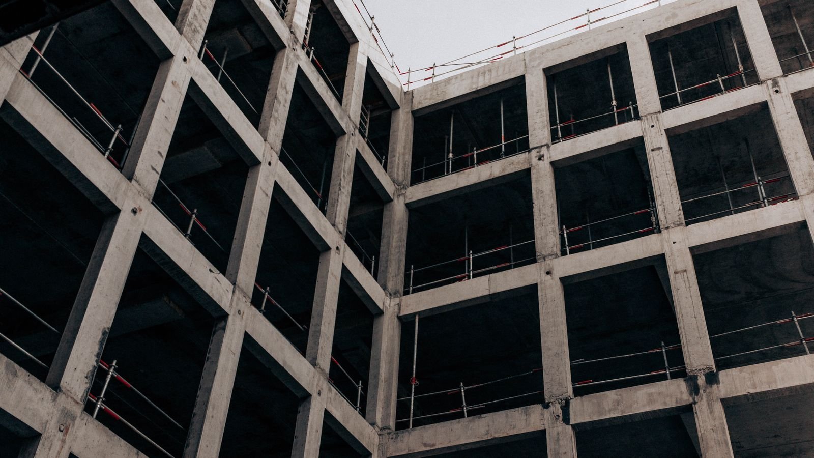 Estrutura de concreto de um prédio inacabado, vista de baixo, com vigas e pilares aparentes