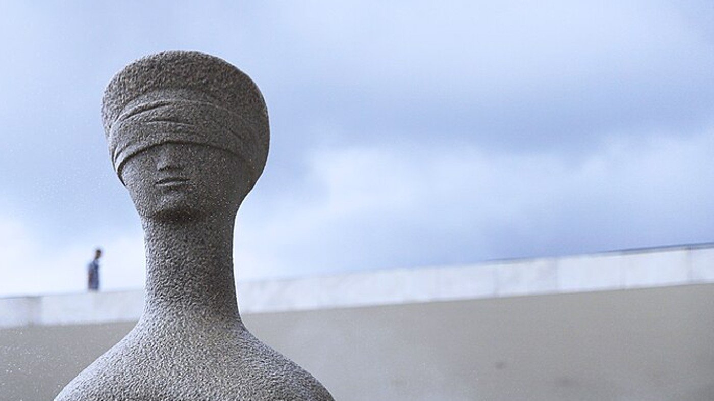 A escultura A Justiça, mulher sentada de olhos vendados, em granito, diante da fachada do Supremo Tribunal Federal