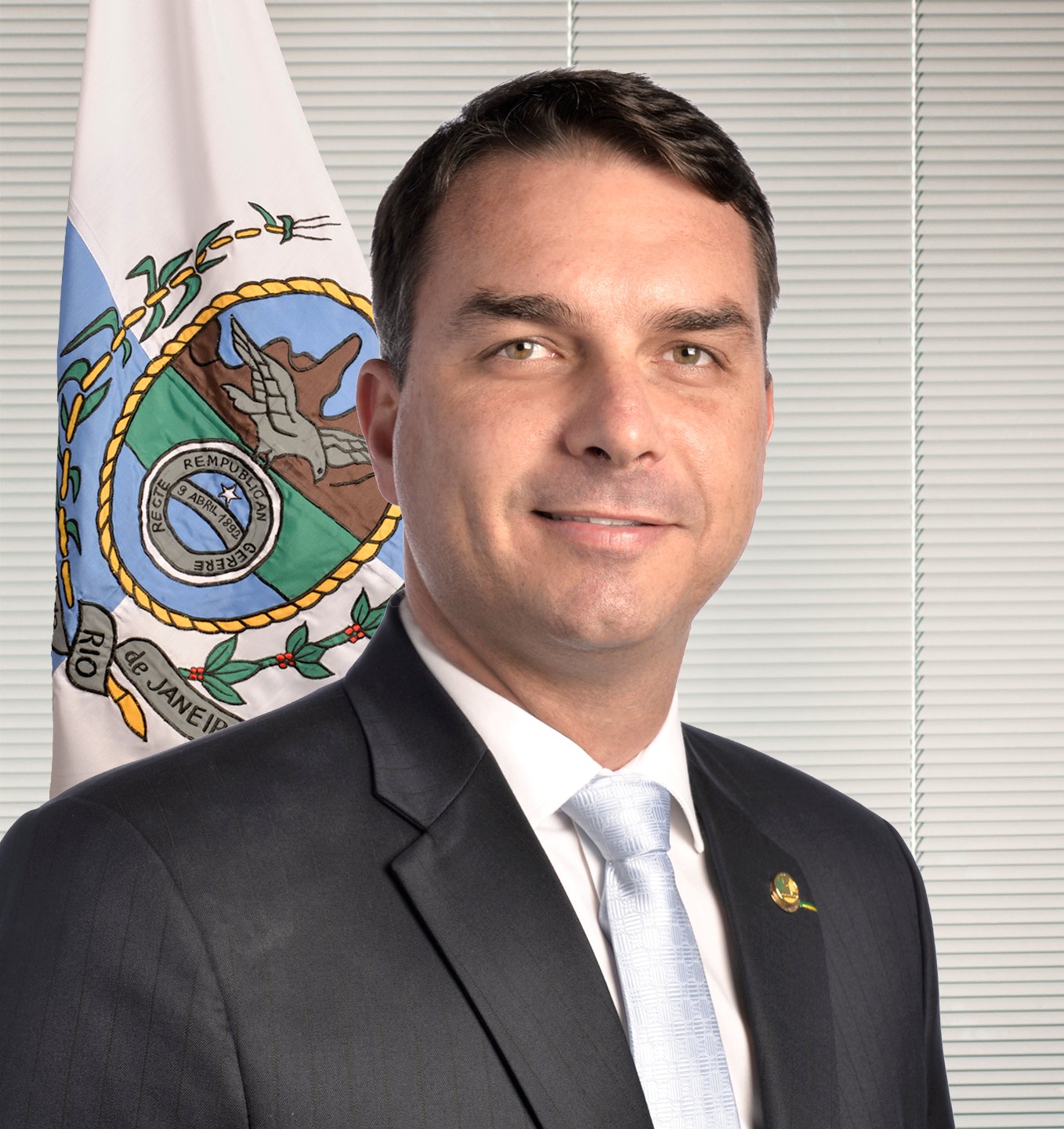 Senador Flávio Bolsonaro em foto oficial de gabinete, com a bandeira do Rio de Janeiro ao fundo