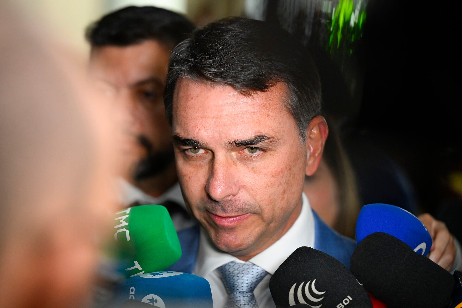 Senador Flávio Bolsonaro cercado de microfones ao conceder entrevista