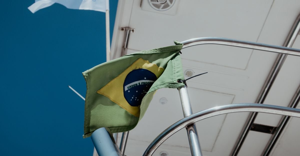 Bandeira do Brasil hasteada em barco sob céu azul (imagem ilustrativa)