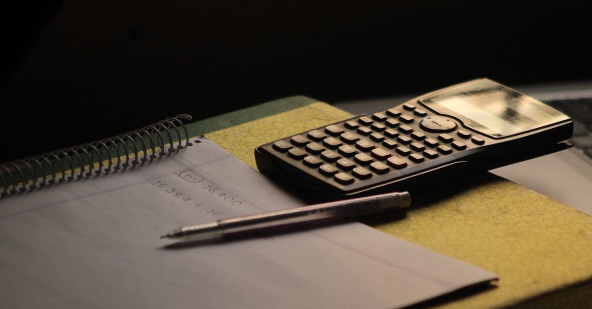 Calculadora científica e caderno de anotações sobre mesa de estudo