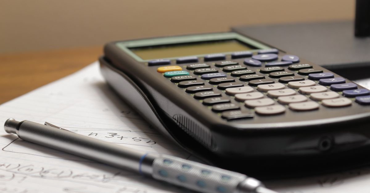Calculadora e caneta sobre anotações com contas