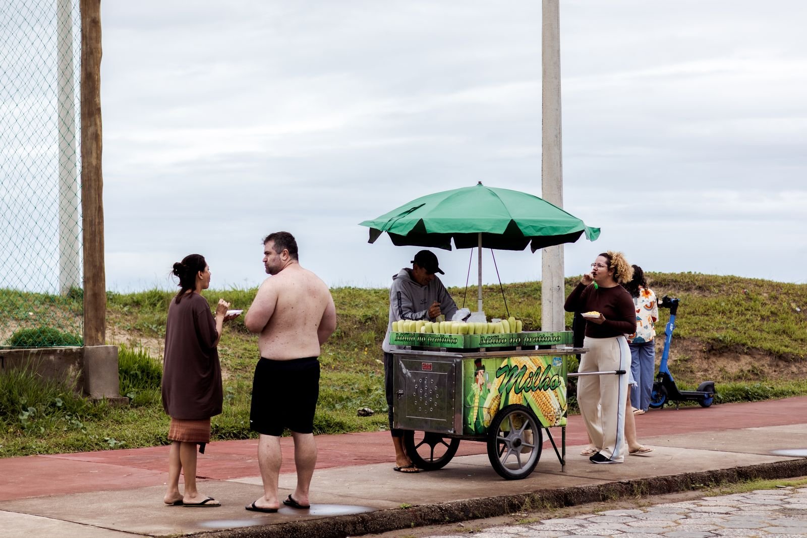 Vendedor de milho atende clientes em calçada à beira-mar, em foto de arquivo no Brasil