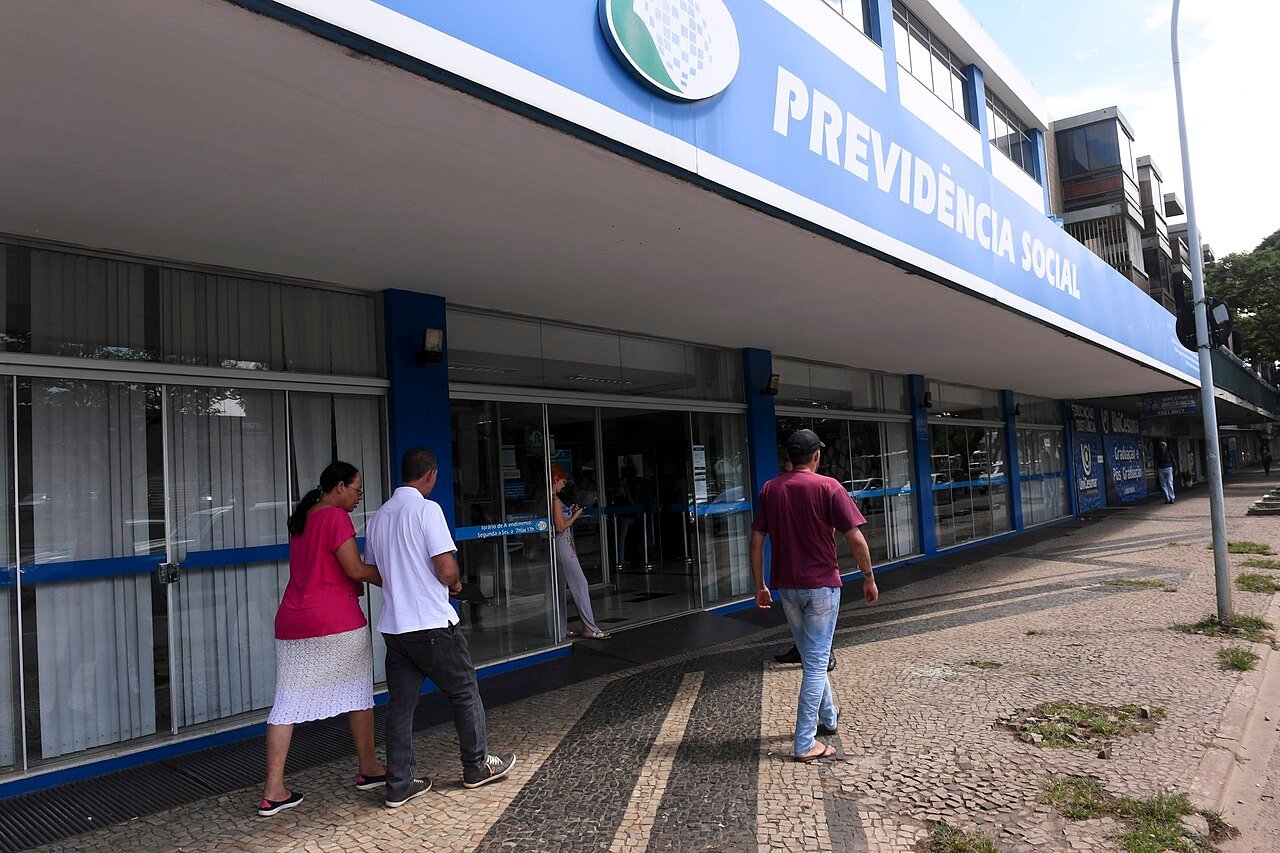 Fachada de agência da Previdência Social com pessoas na calçada