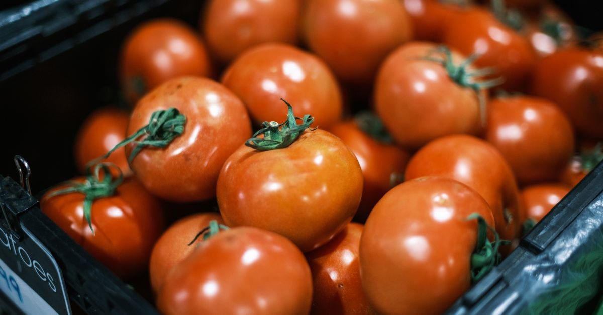 Tomates vermelhos empilhados em caixa de feira, em foto de arquivo