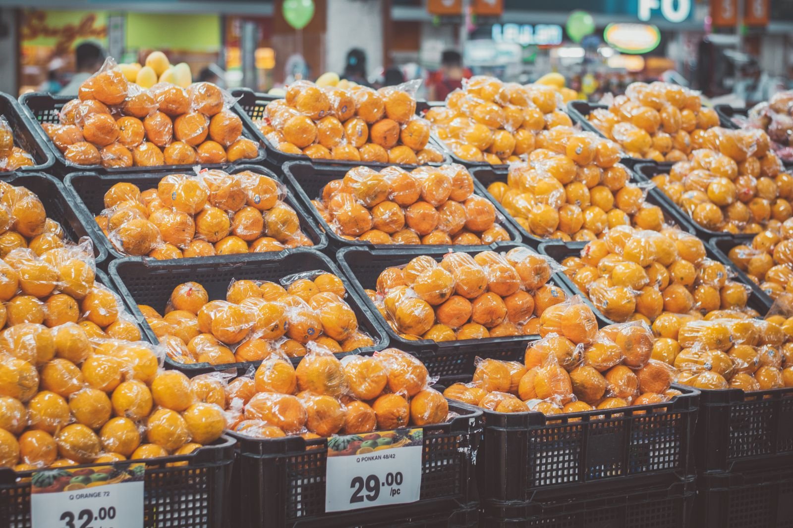 Bandejas de laranjas embaladas em plástico, com etiquetas de preço, em corredor de supermercado