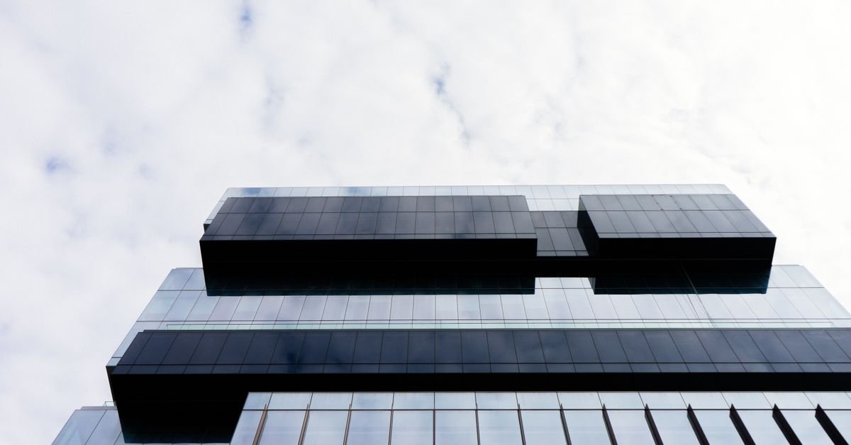 Fachada de vidro de edifício corporativo vista de baixo para cima contra o céu claro