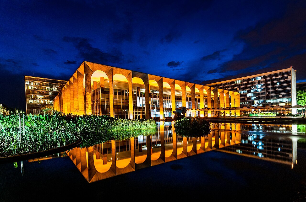 Palácio do Itamaraty iluminado à noite, refletido no espelho d'água, em Brasília