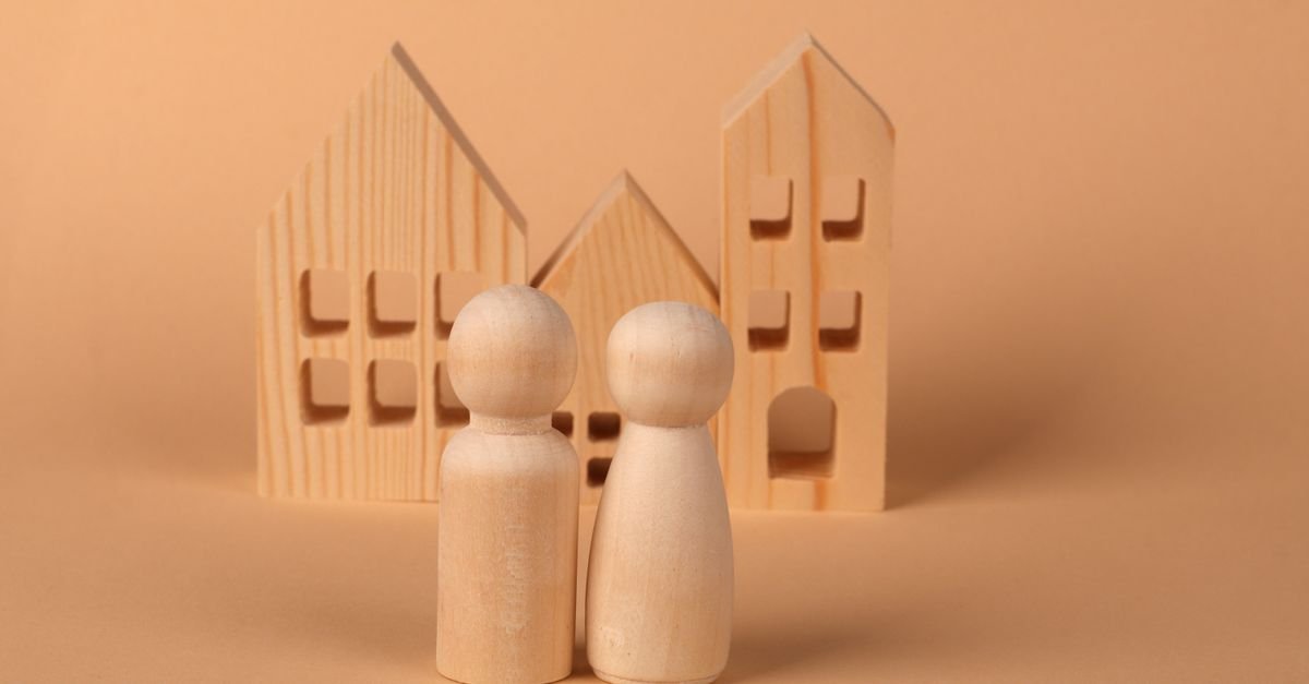 Figuras e casas de madeira sobre fundo neutro representando patrimônio familiar