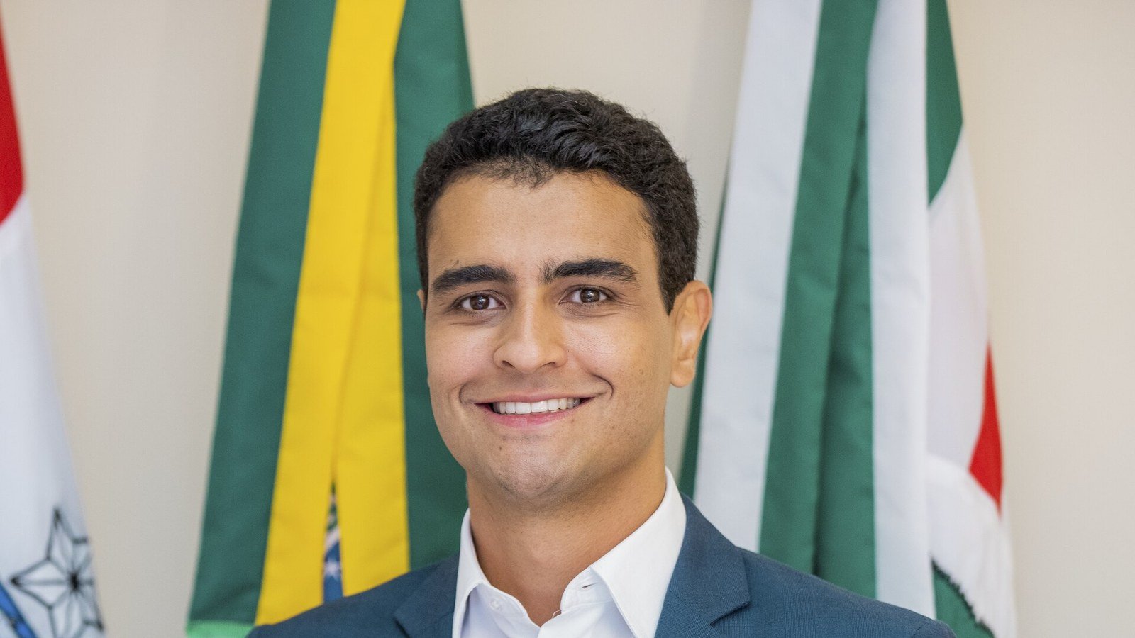 Retrato de JHC diante das bandeiras do Brasil e de Alagoas