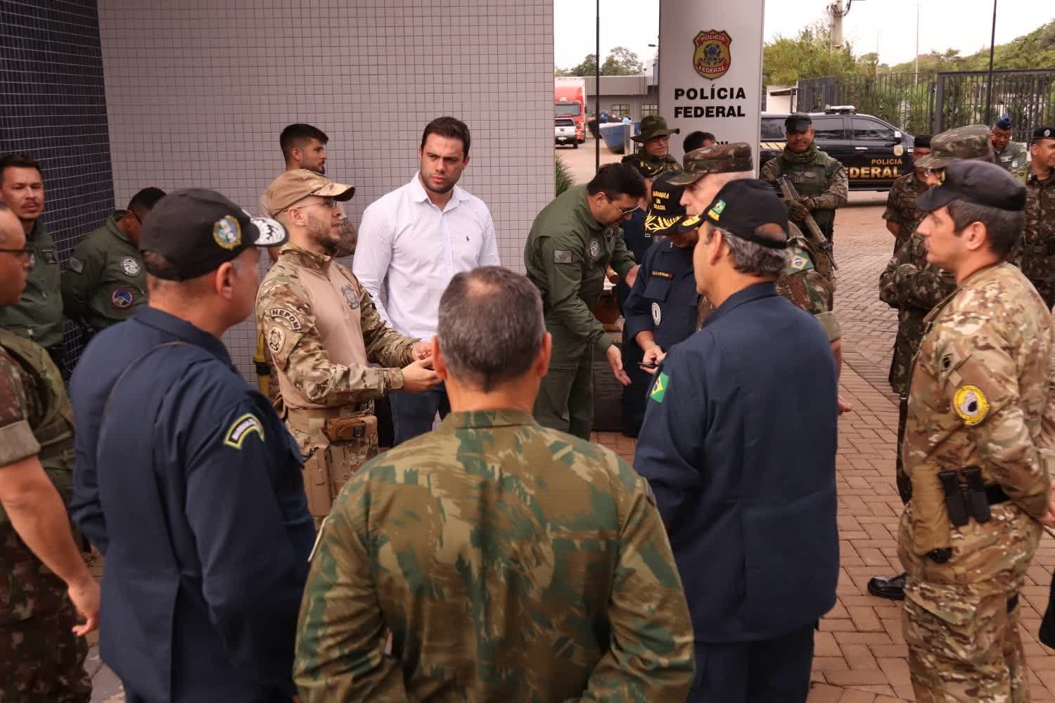 Autoridades civis e militares reunidas na entrada de uma unidade da Polícia Federal durante operação de fronteira