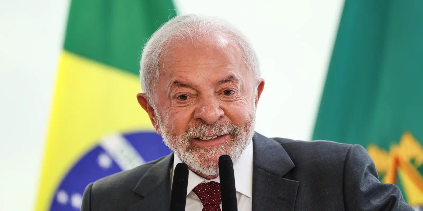 O presidente Luiz Inácio Lula da Silva fala ao microfone diante da bandeira do Brasil e do estandarte presidencial