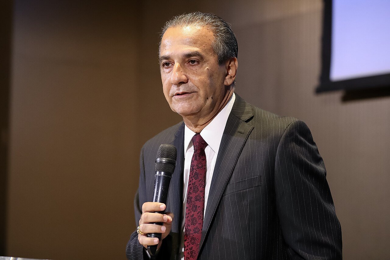 Silas Malafaia fala ao microfone durante evento, de terno escuro e gravata vermelha