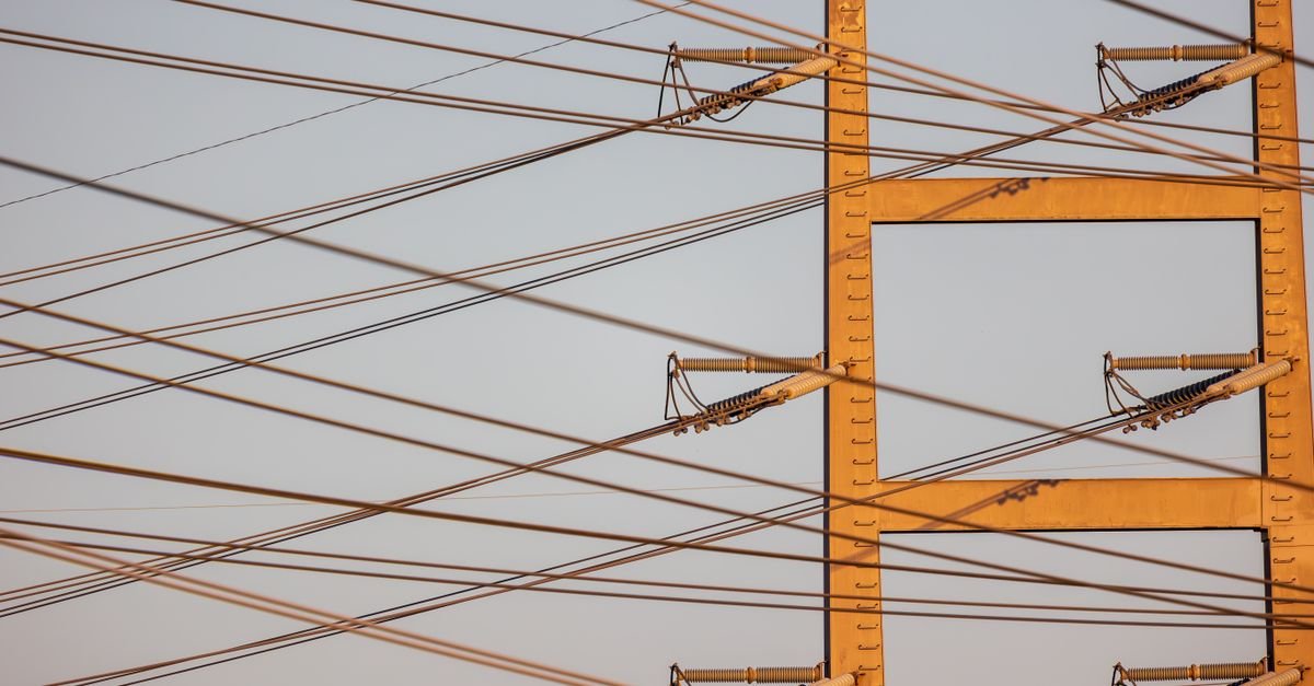 Torre metálica de transmissão de energia com cabos de alta tensão contra o céu ao entardecer