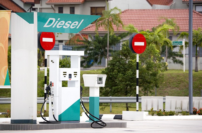 Bomba de abastecimento de diesel com a palavra Diesel em letreiro sobre a cobertura de um posto de combustíveis