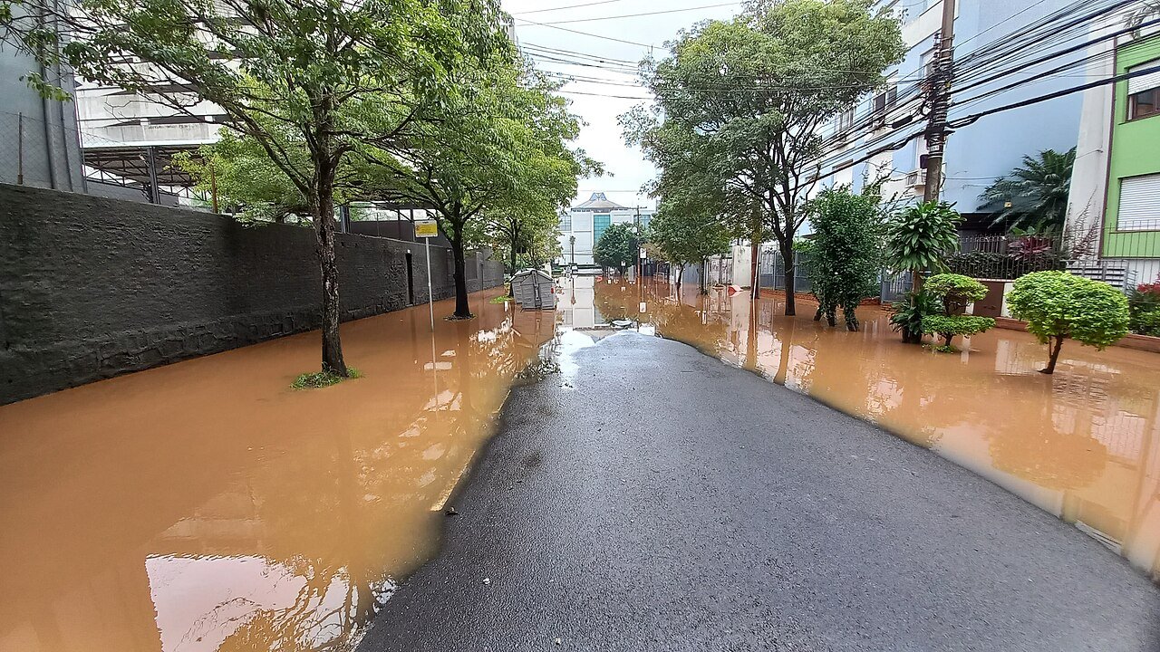 Rua residencial tomada por água barrenta durante enchente em Porto Alegre