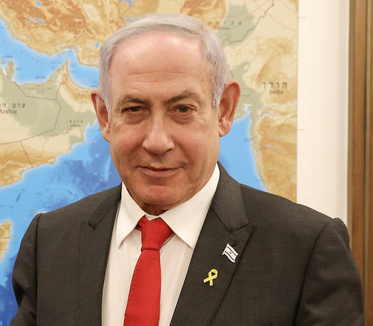 O primeiro-ministro de Israel, Benjamin Netanyahu, de terno escuro, diante de um mapa da região
