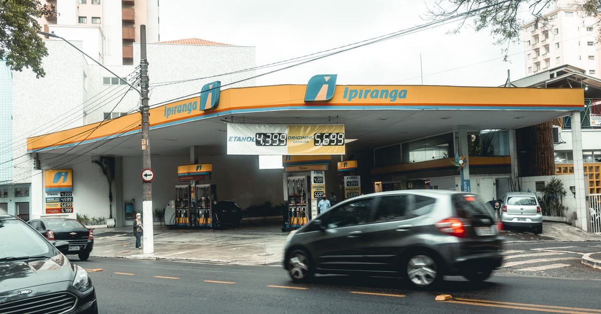 Posto de combustíveis em rua movimentada, com painel de preços de etanol e gasolina em reais